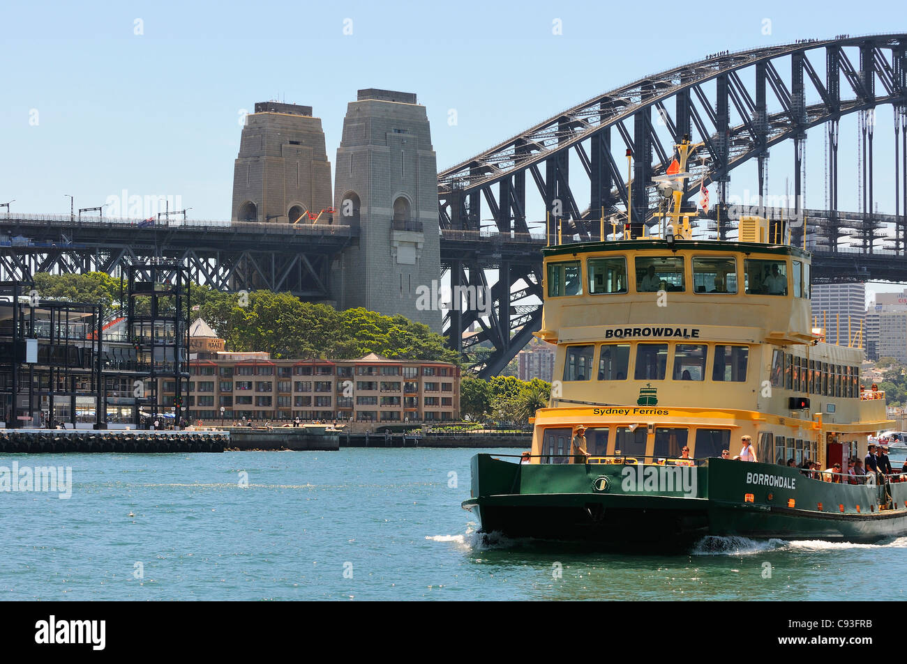 Sydney Ferry coming into Circular Quay terminal with Sydney Harbour bridge Overseas Passenger Terminal, Park Hyatt Hotel in view - Australia Stock Photo