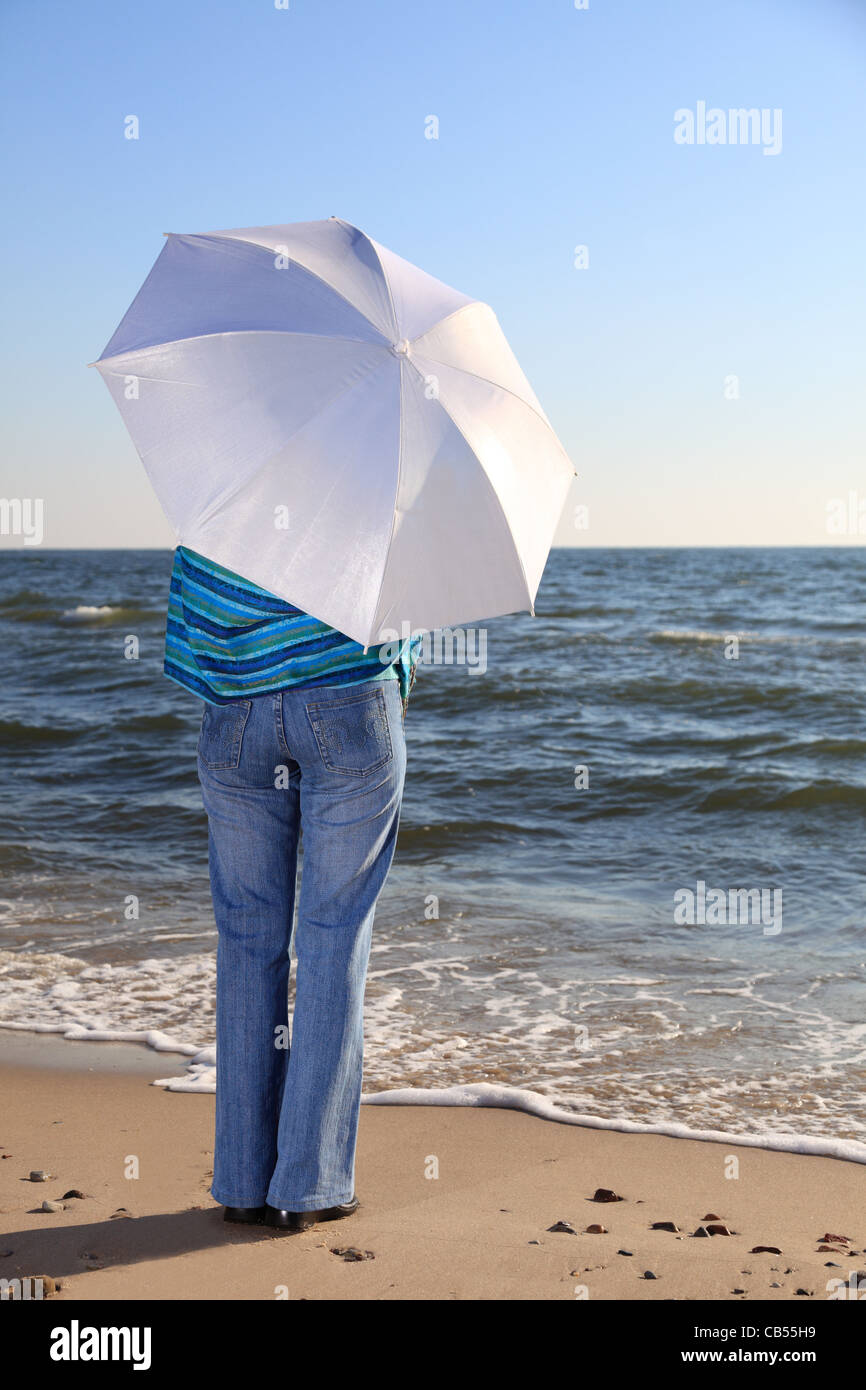 blue woman and parasol at sea shore Stock Photo