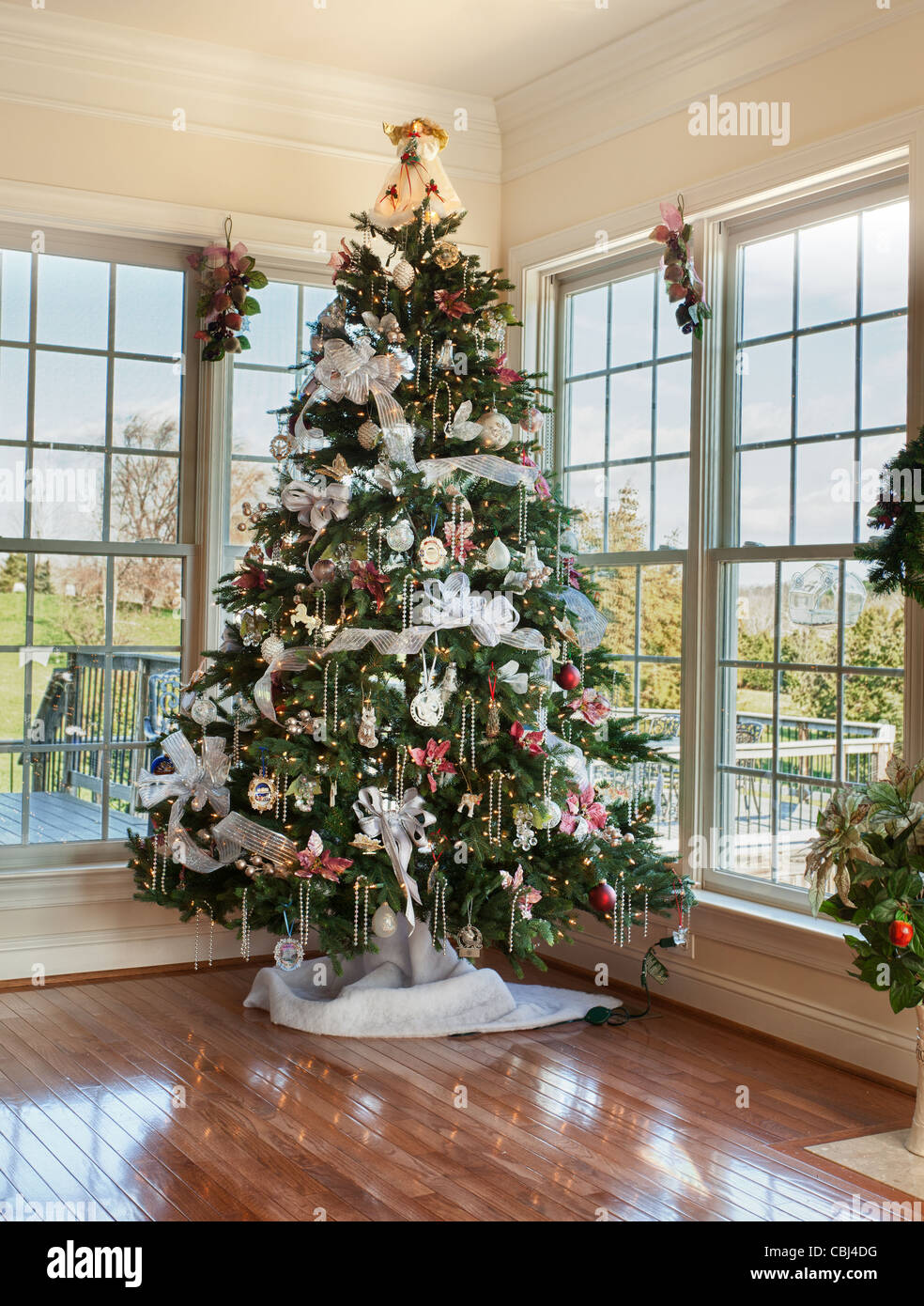 Christmas tree decorated with silver and white ribbons and ornaments in family home Stock Photo