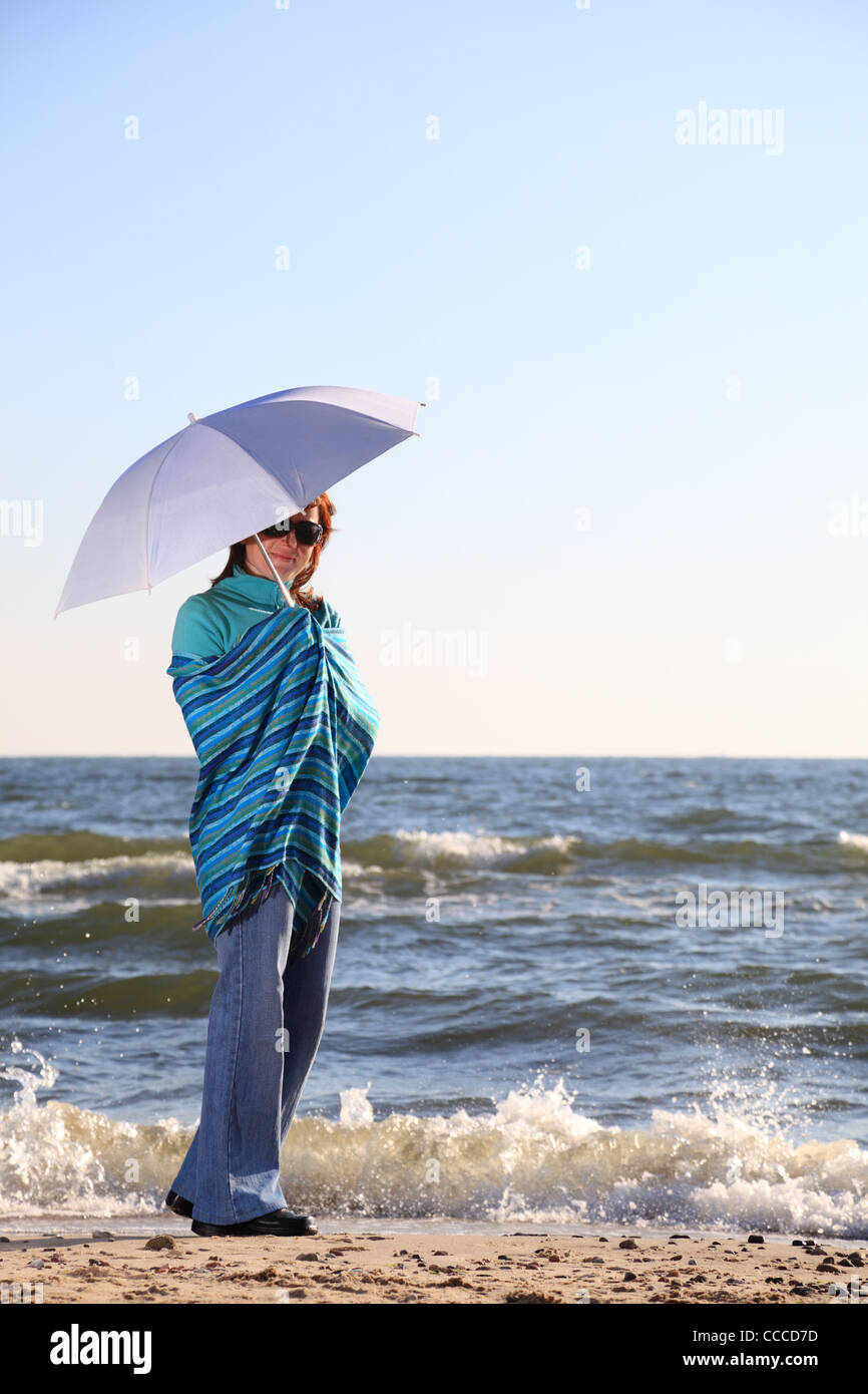 blue woman and parasol at sea shore Stock Photo