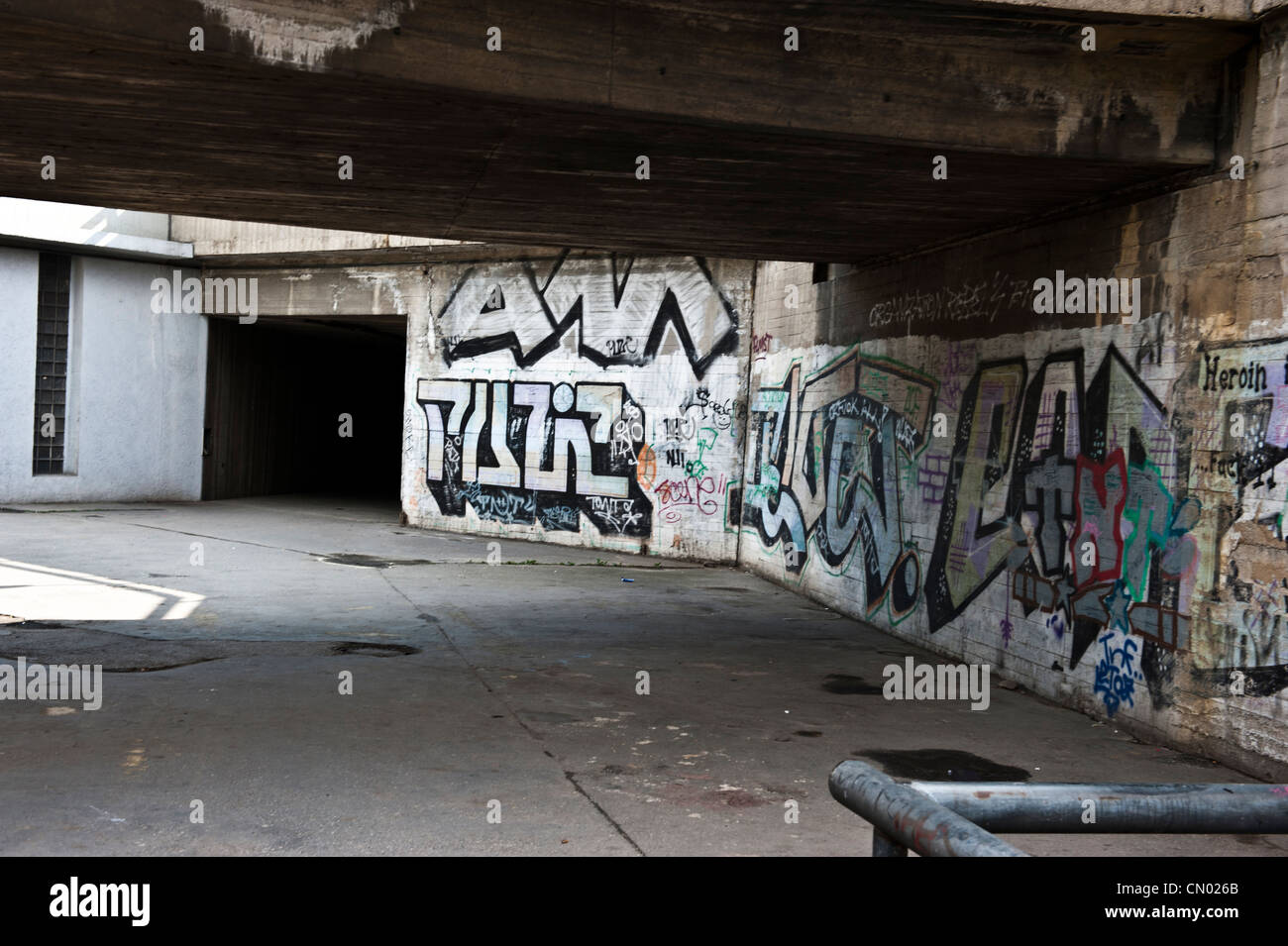 Colorful letters of graffiti splattered along an urban underpass. Stock Photo