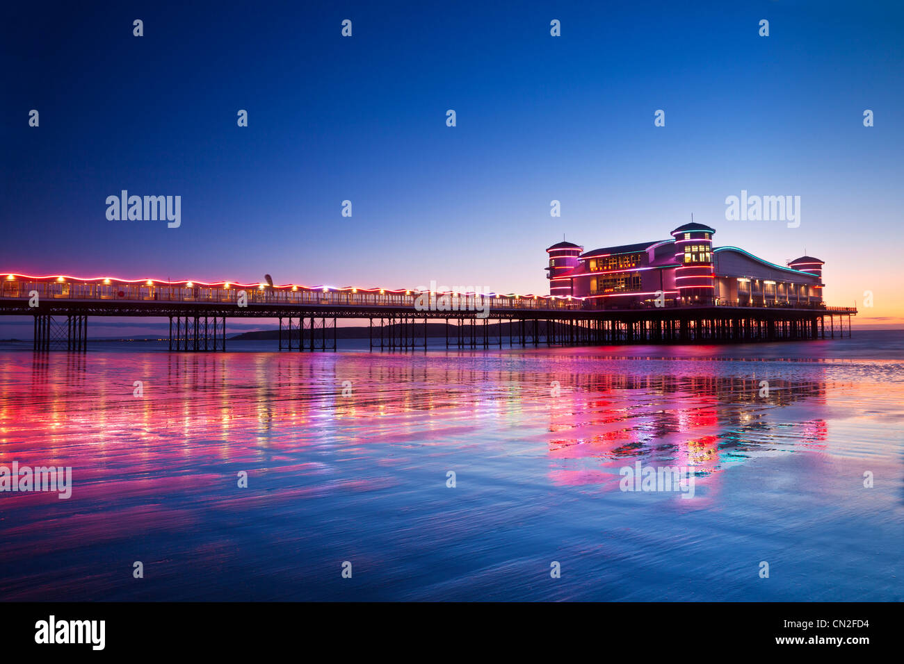 Twilight over the illuminated Grand Pier at Weston-Super-Mare, Somerset, England, UK reflected in wet sand at high tide. Stock Photo