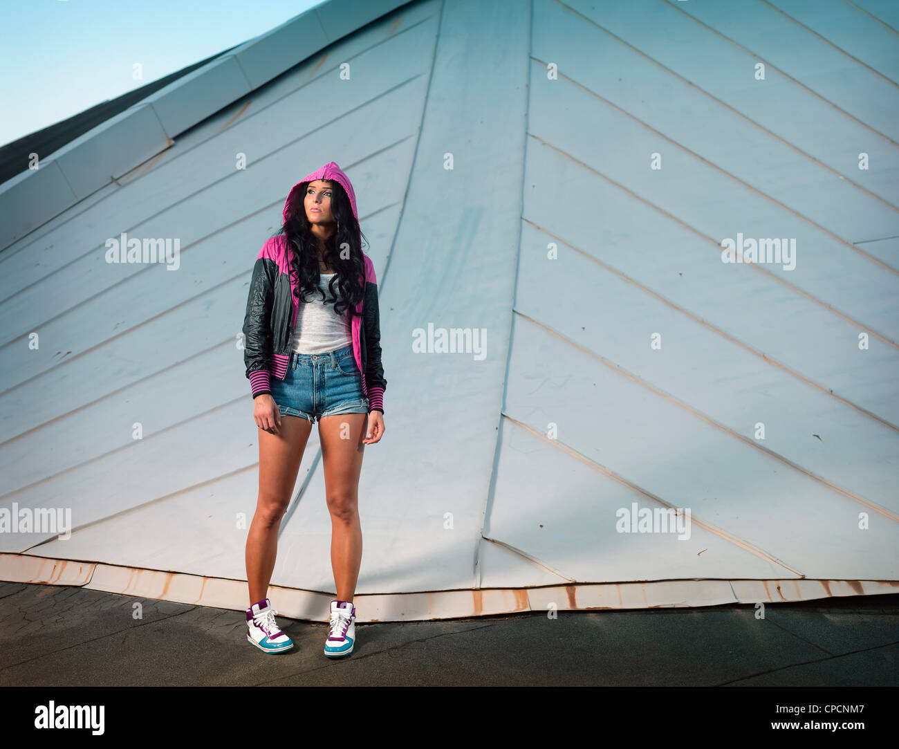 Woman wearing hoodie on urban rooftop Stock Photo