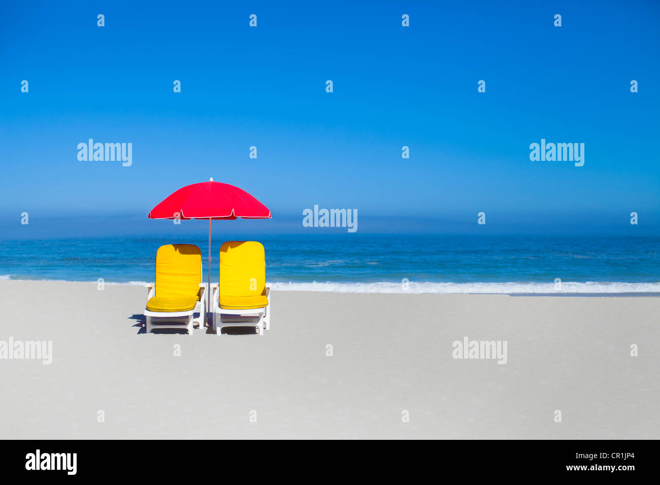 Empty lawn chairs and umbrella on beach Stock Photo