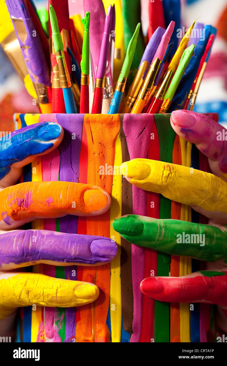 Close-up of woman holding multicolored paint can with painted fingers Stock Photo