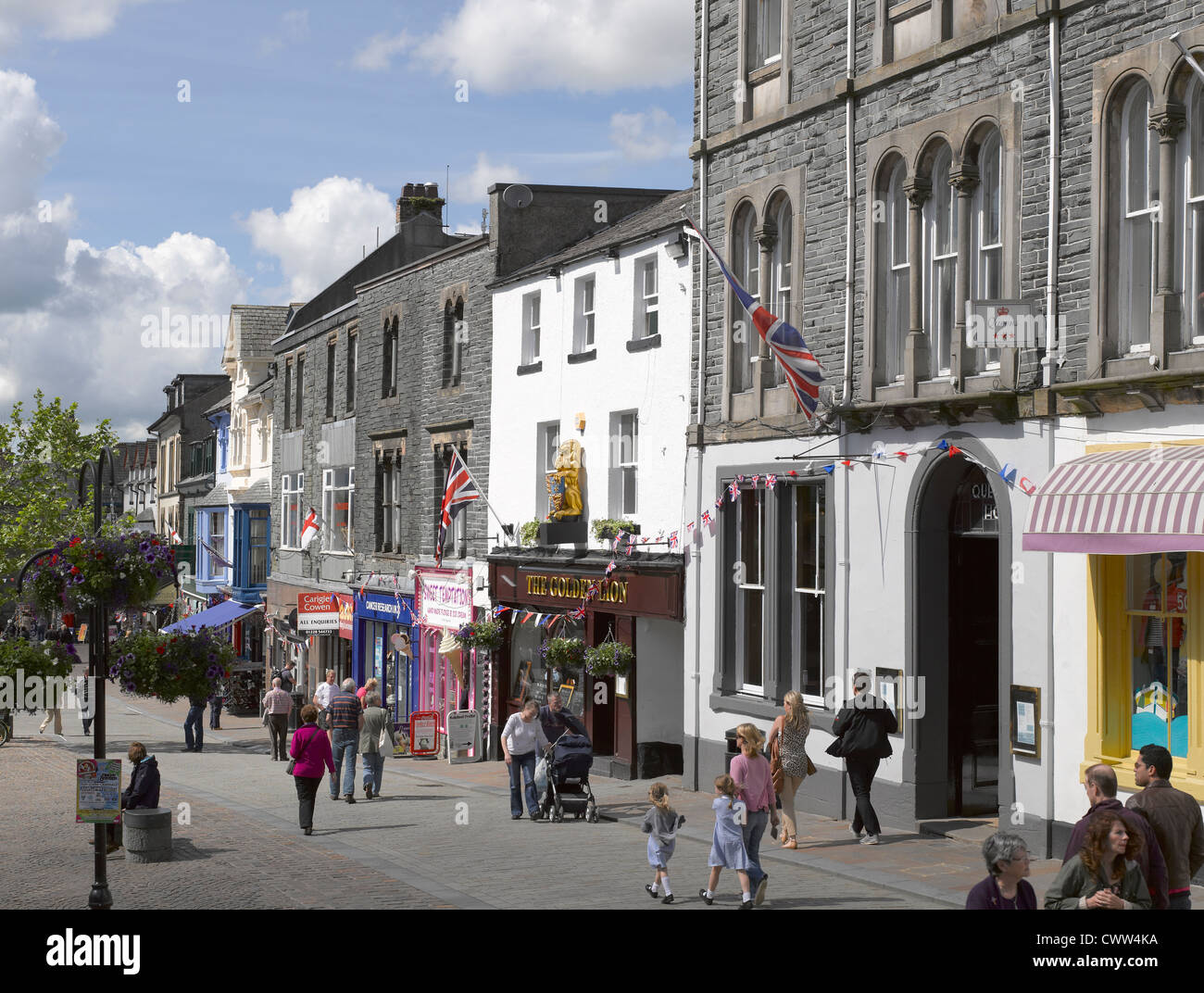 People tourists visitors and shops stores in the town centre in summer Market Square Keswick Cumbria England UK United Kingdom GB Great Britain Stock Photo