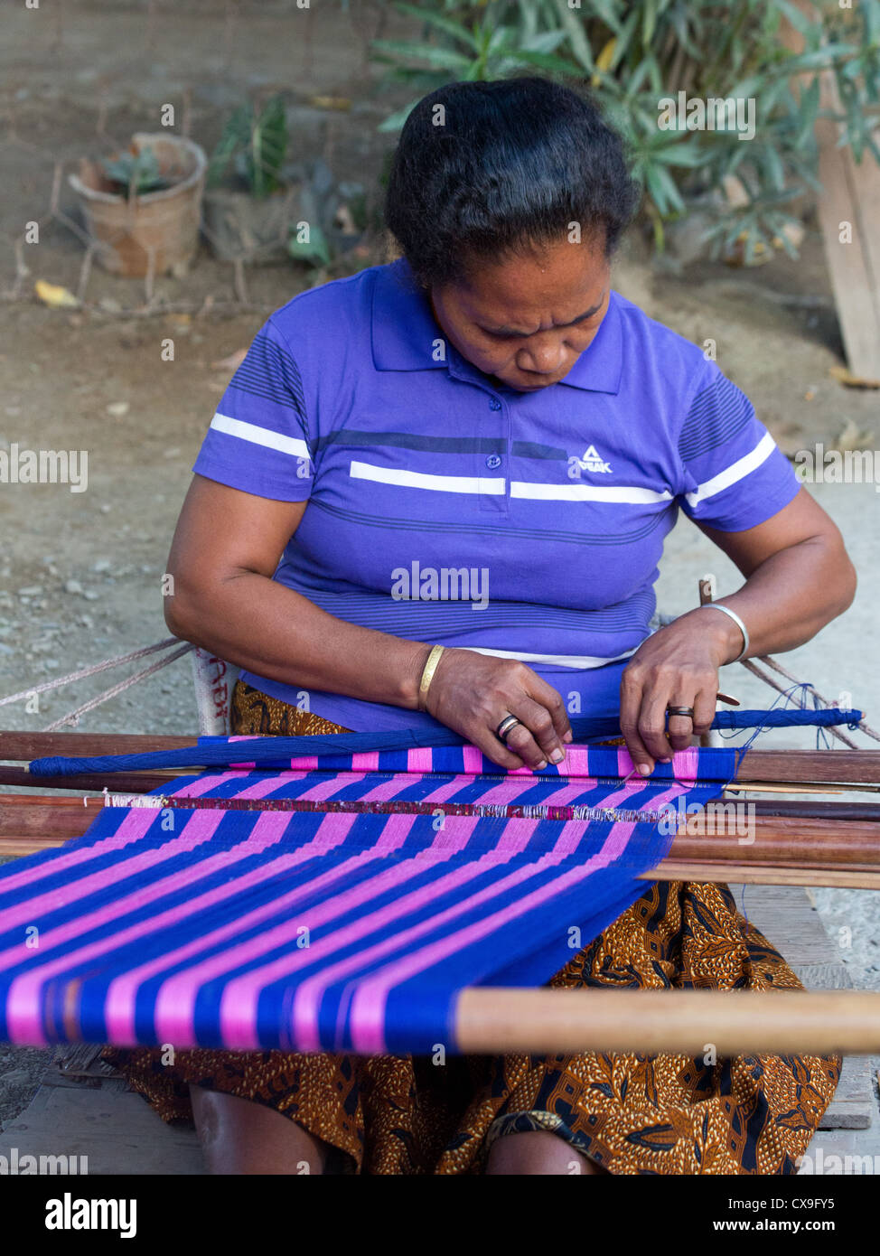 Woman weaving colourful tais fabric on a loom, Dili, East Timor Stock Photo