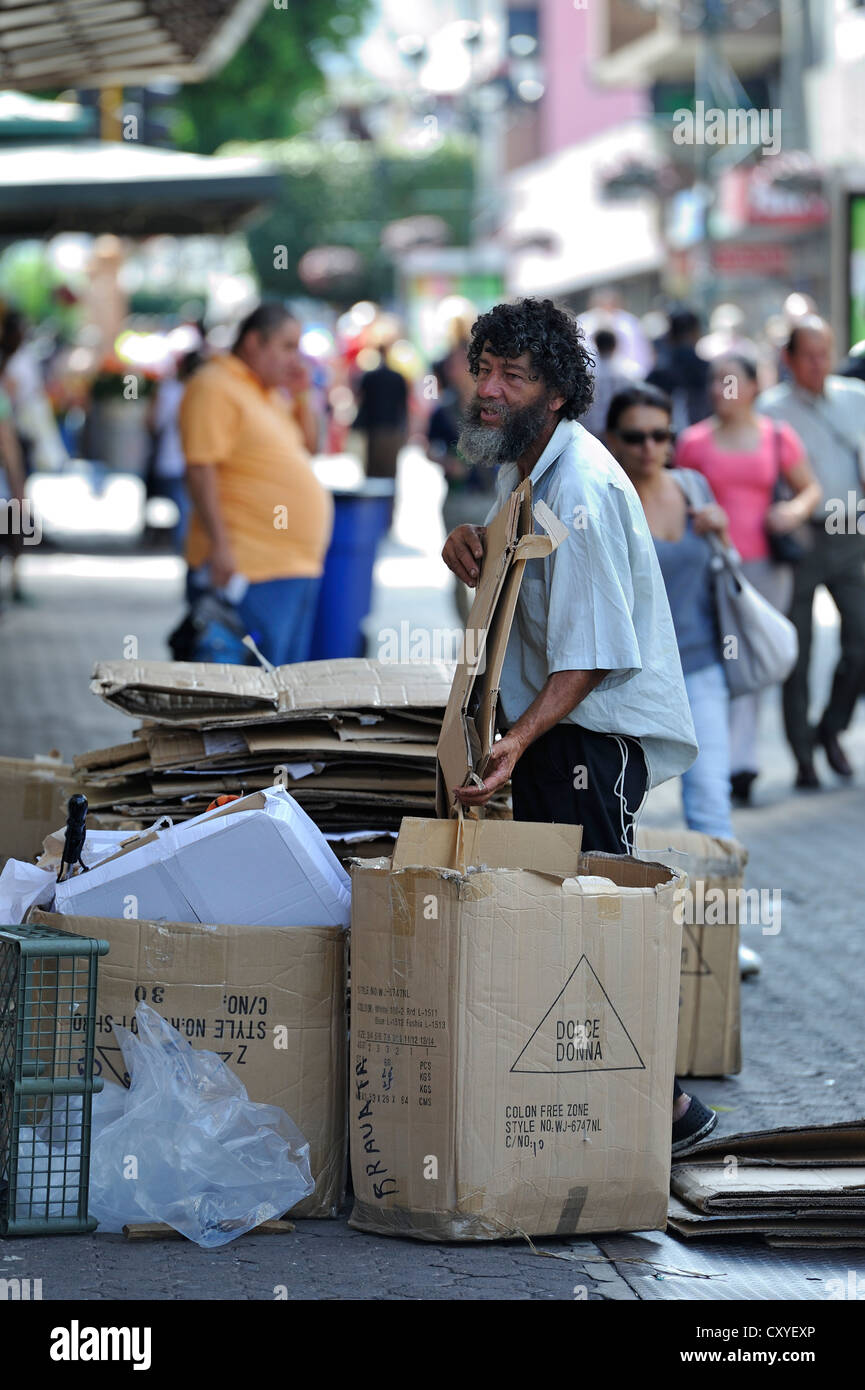 Poor man sorting recyclables or resources, cardboard boxes outside a shop, in order to sell them to a recycling plant Stock Photo