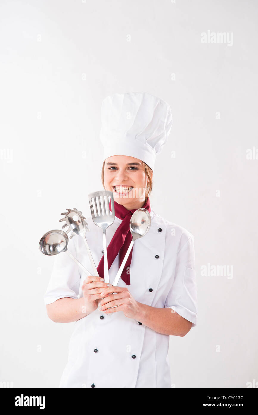 Young chef holding kitchen utensils Stock Photo