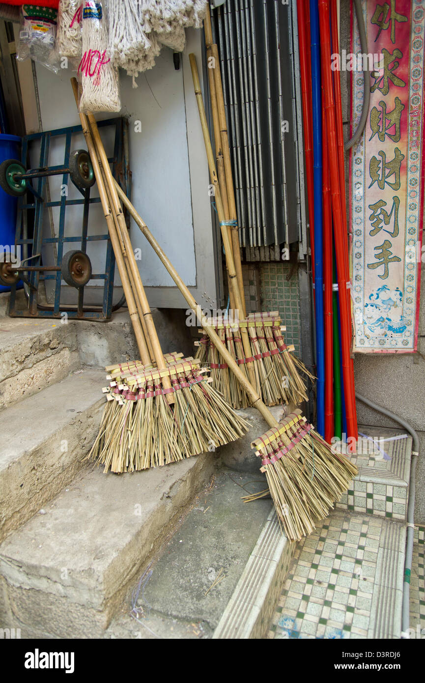 Handmade brooms sit on the steps outside a shop in Hong Kong Stock Photo