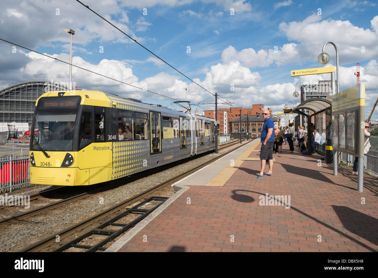 Passengers waiting on platform for Metrolink tram arriving at Deansgate-Castlefield station in Manchester city centre England UK Stock Photo