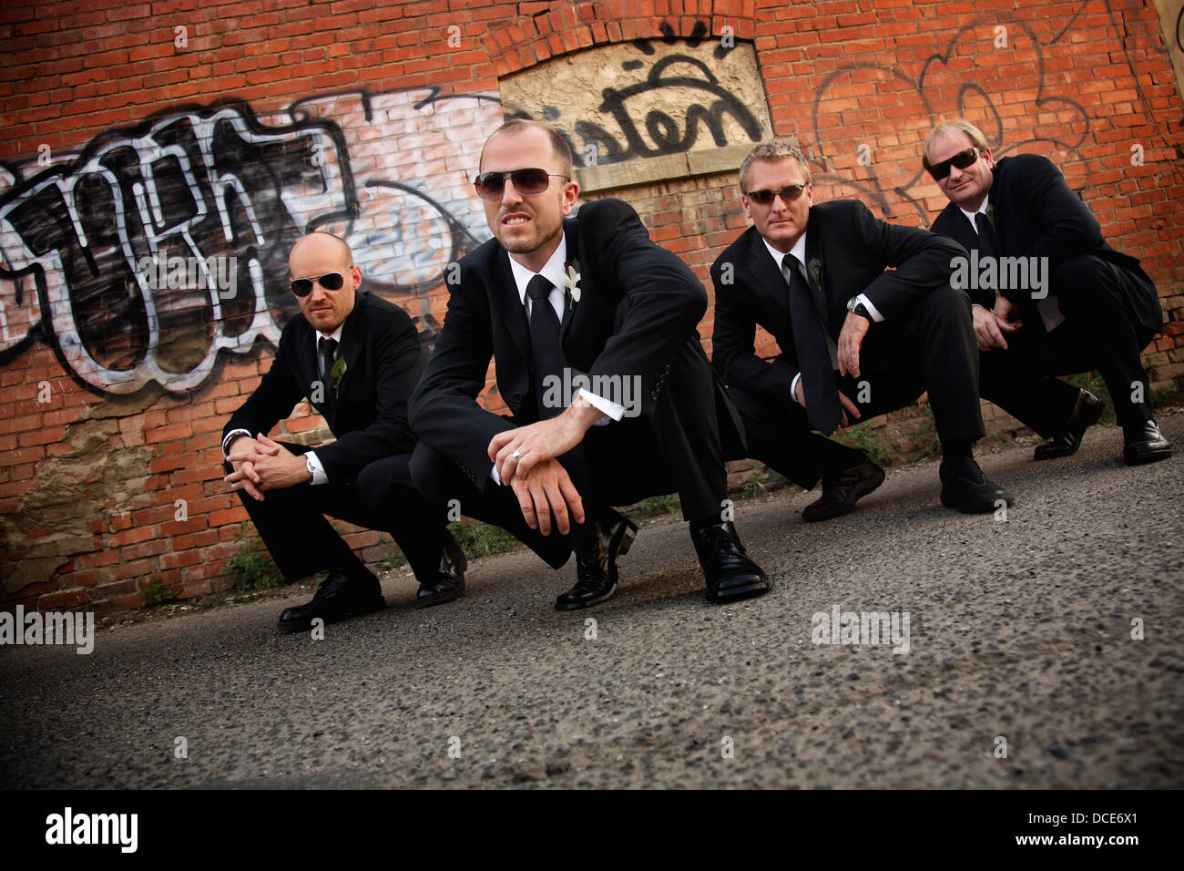 Groomsmen Posing Like A Gang In Graffiti Covered Alley Stock Photo