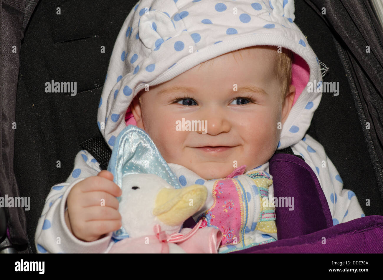 Smiling eight month old baby girl with Jemima Puddle Duck doll Stock Photo