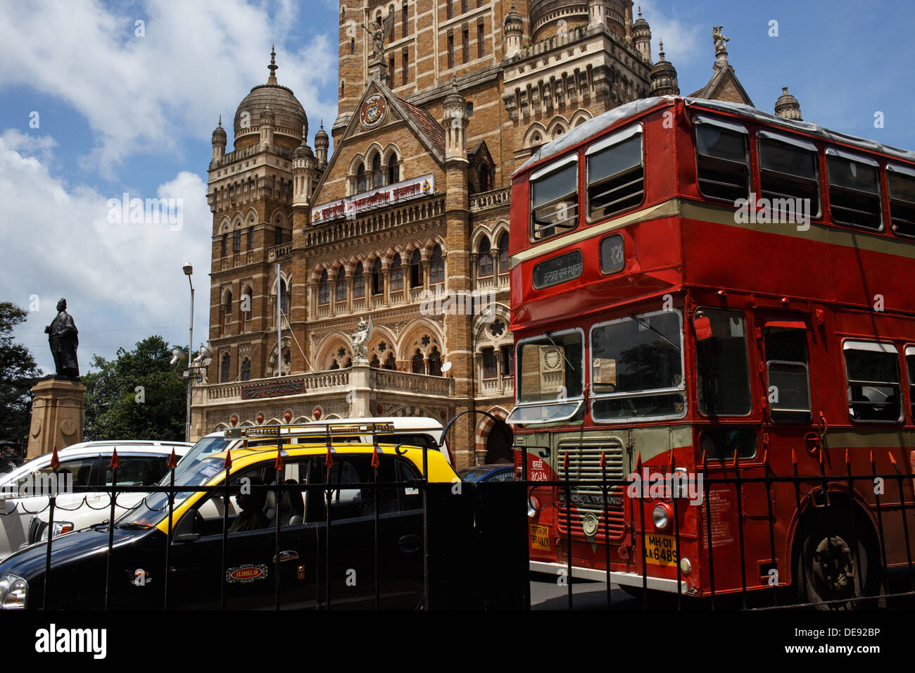 A red double decker bus, black taxi and cars in the traffic with the  Municipal Corporation Building in the background, Mumbai Stock Photo