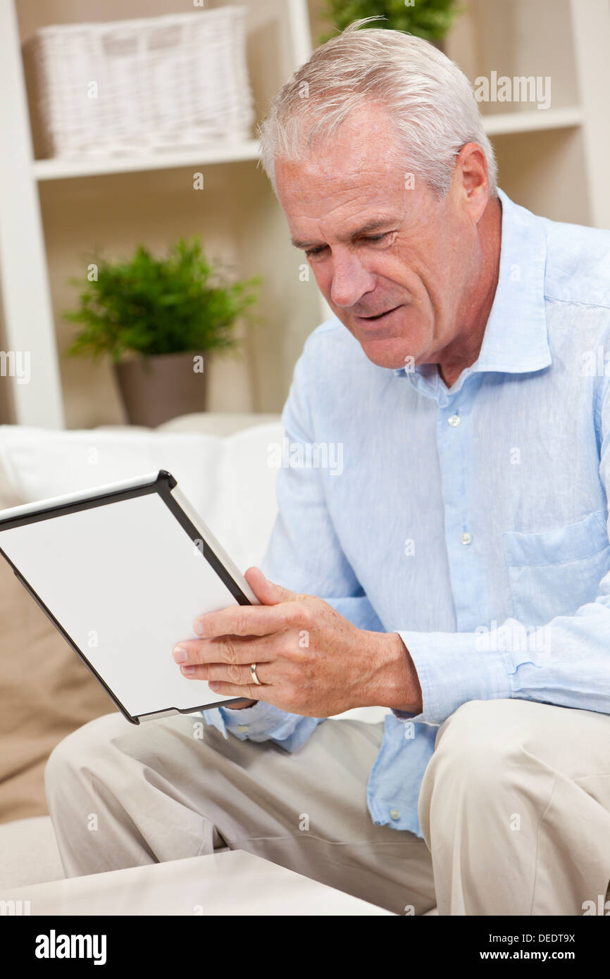 Happy senior man sitting at home using a tablet computer Stock Photo