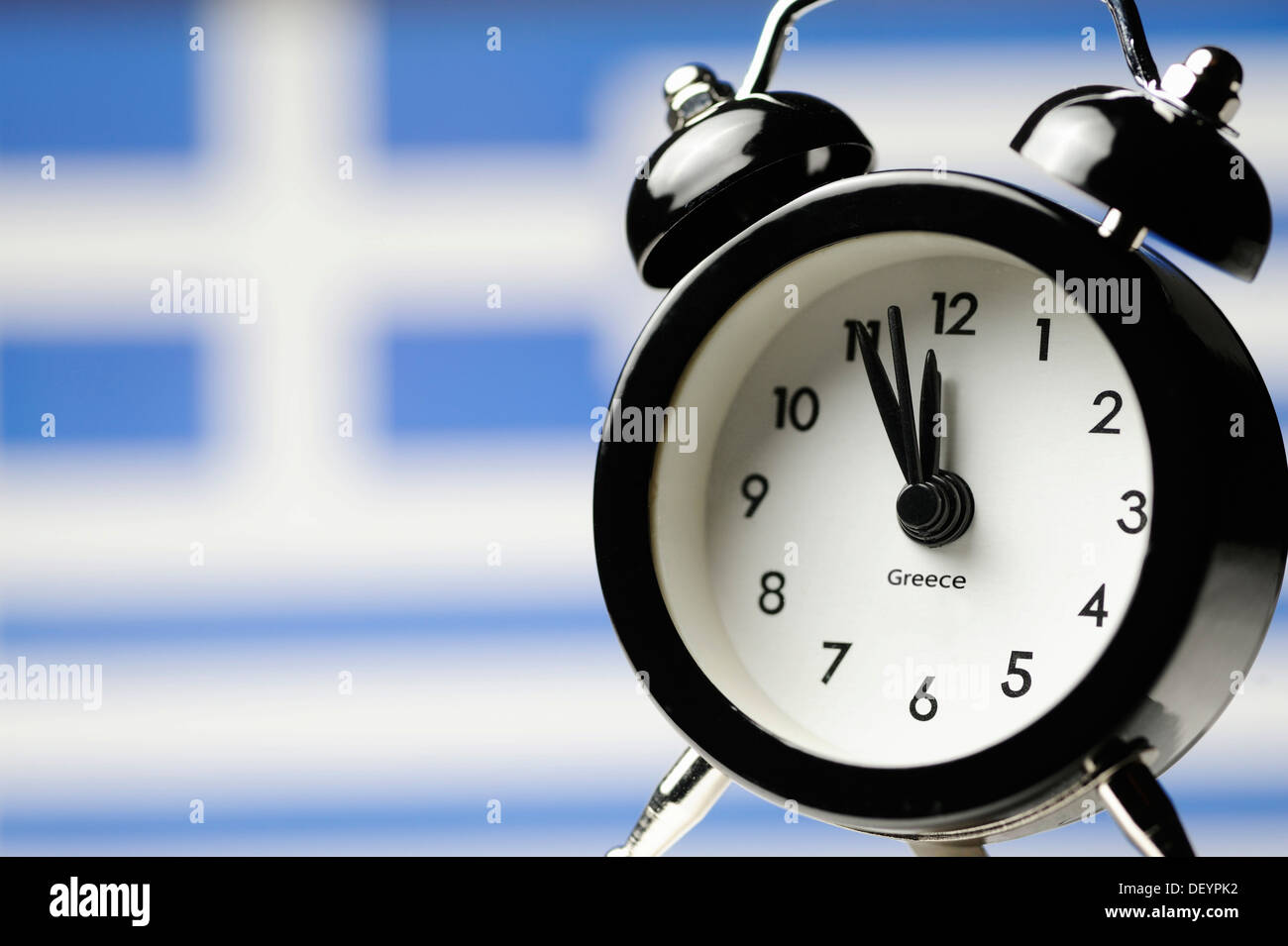 Five to twelve on an alarm clock display in front of Greek national flag, symbolic image, threat of impending national Stock Photo