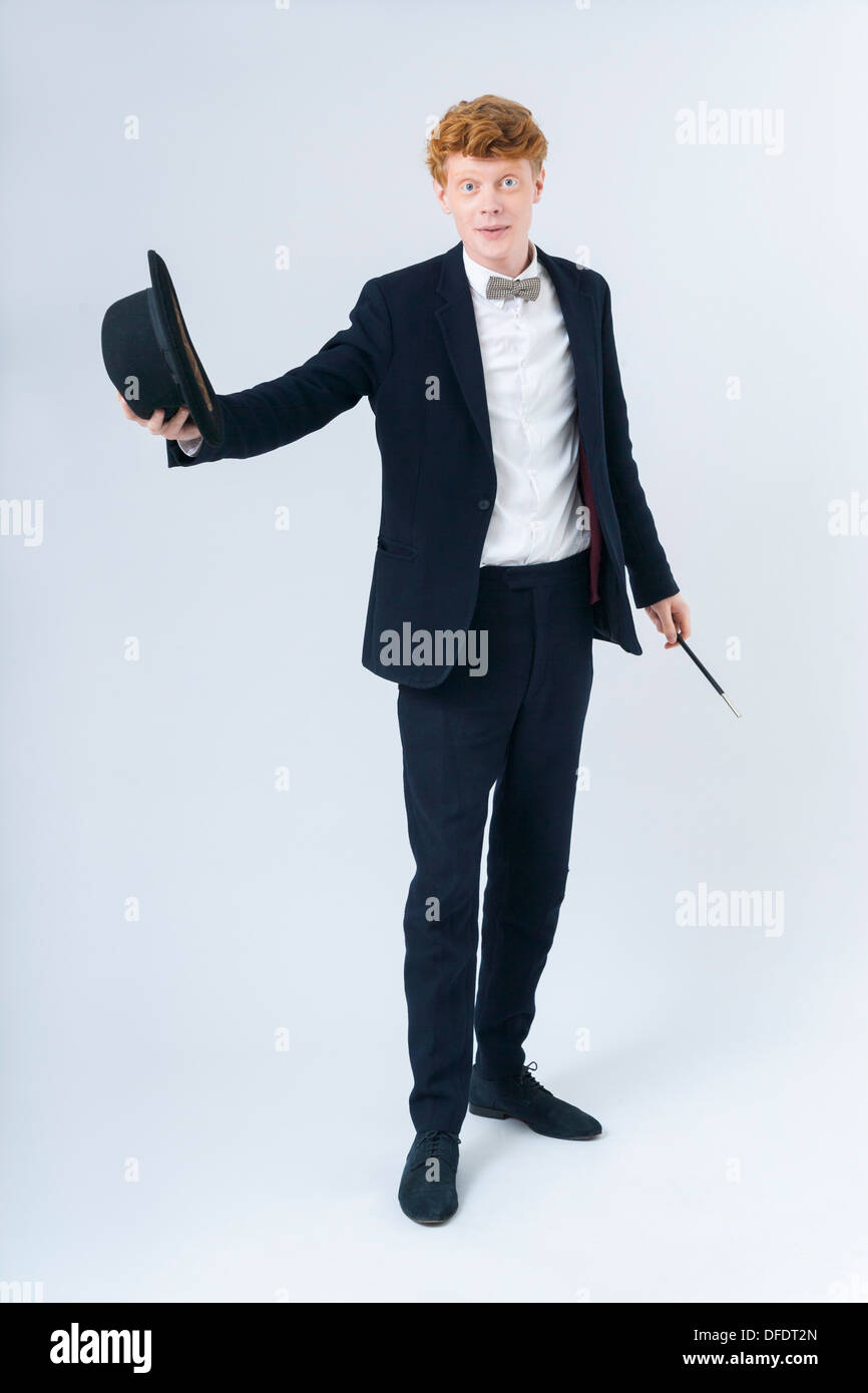 Portrait of young man holding hat and magic wand Stock Photo