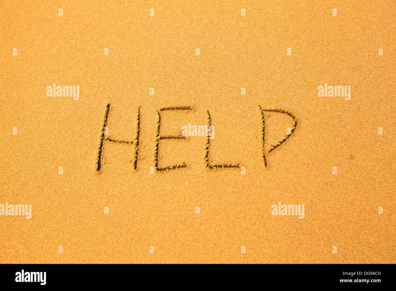 Help - written in sand on beach texture. Stock Photo