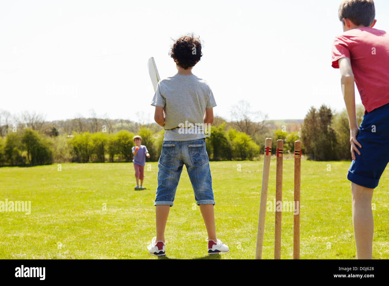 Boys playing cricket on field Stock Photo