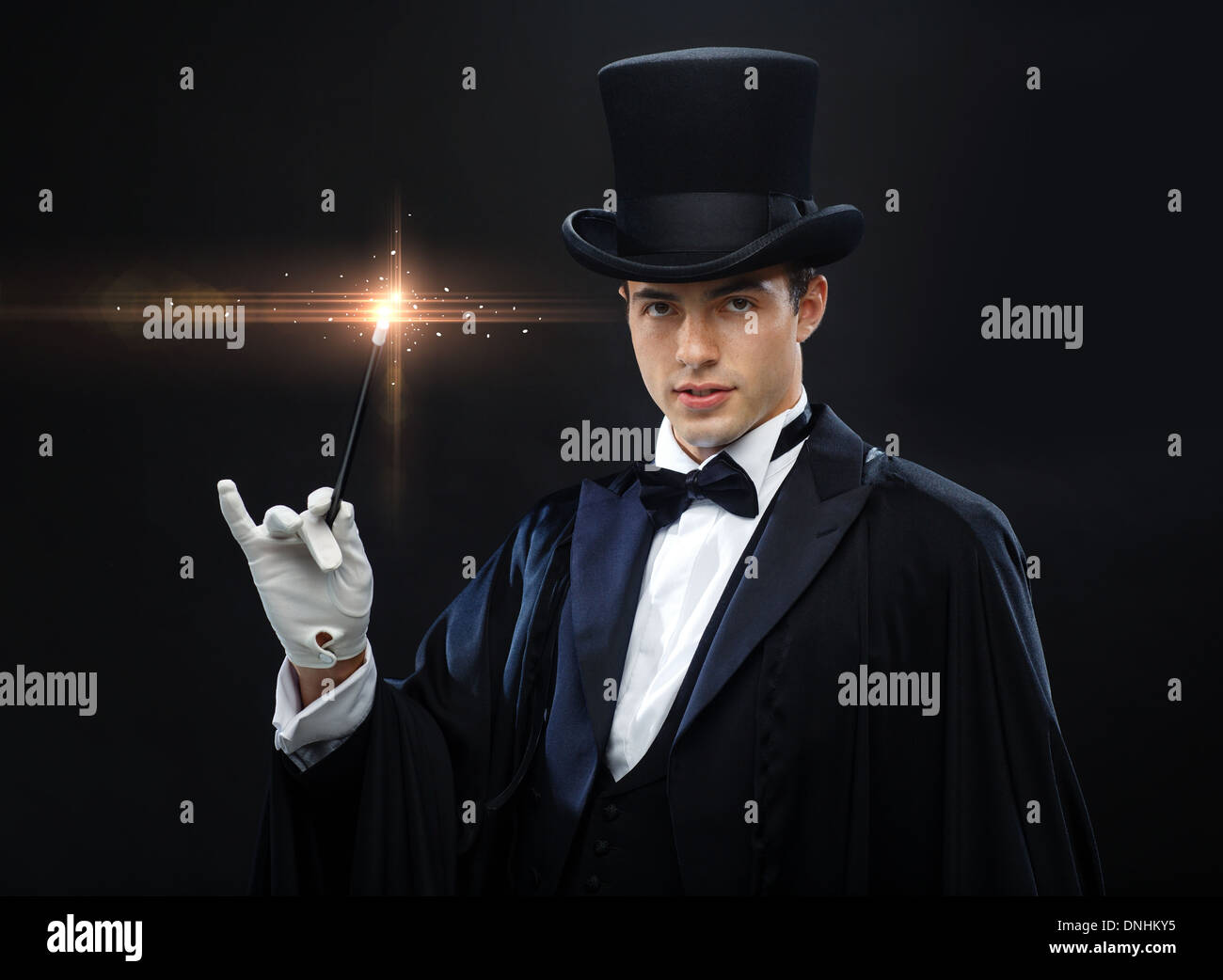 magician in top hat with magic wand showing trick Stock Photo