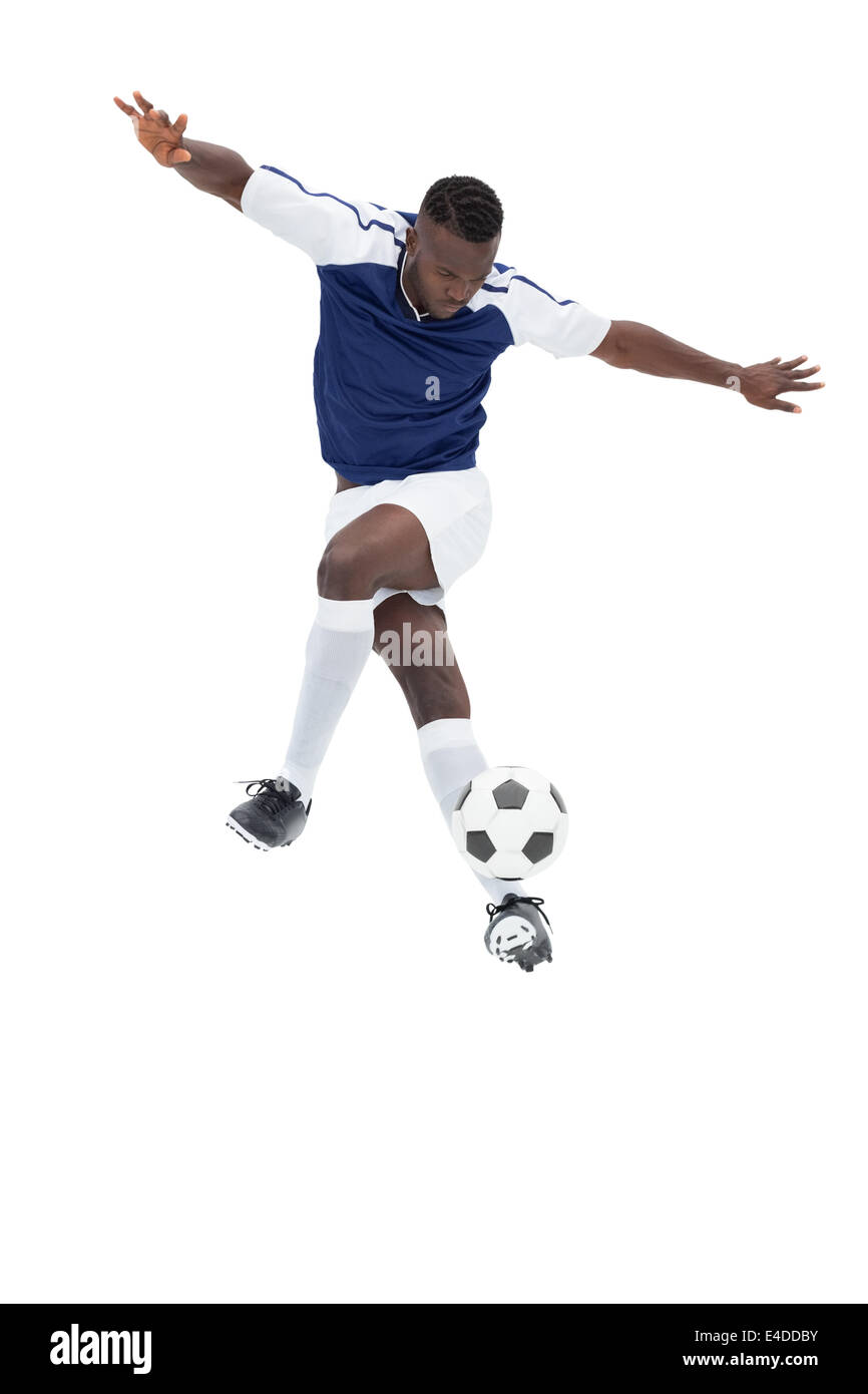 Football player in blue jersey controlling ball Stock Photo