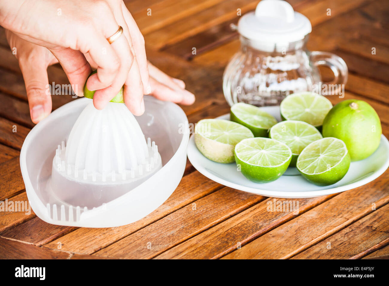 Hand squashing fresh lime on wood counter Stock Photo