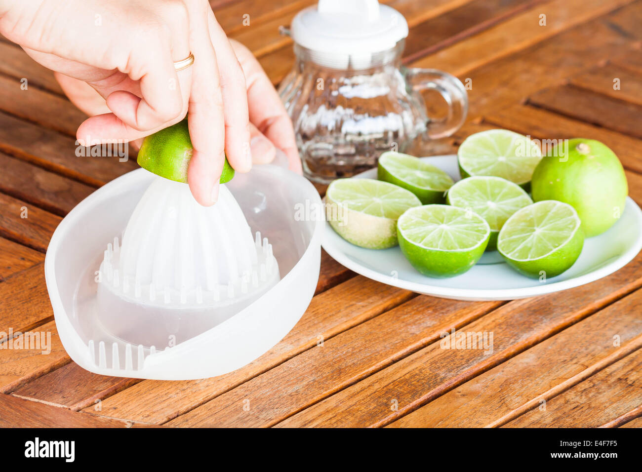 Hand squashing fresh lime on wood table Stock Photo