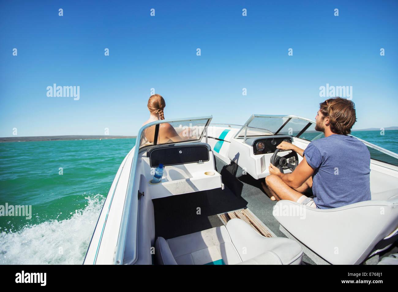 Man steering boat on water with girlfriend Stock Photo