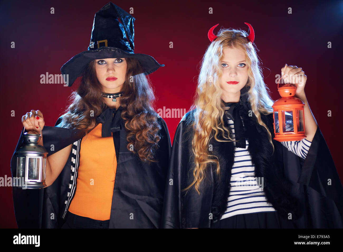 Halloween girls in black cloaks holding lanterns Stock Photo