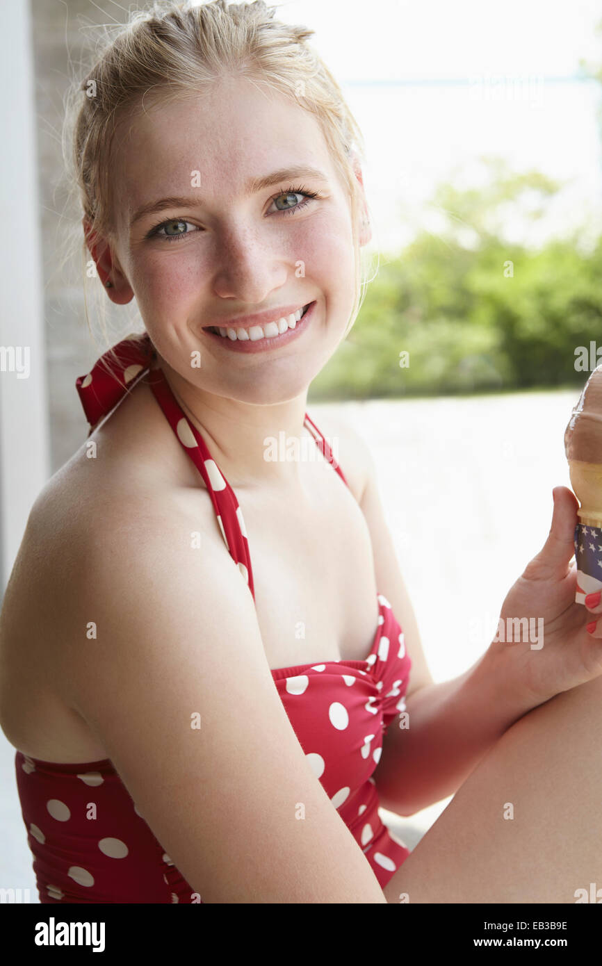 Smiling woman in swimsuit eating ice cream cone Stock Photo