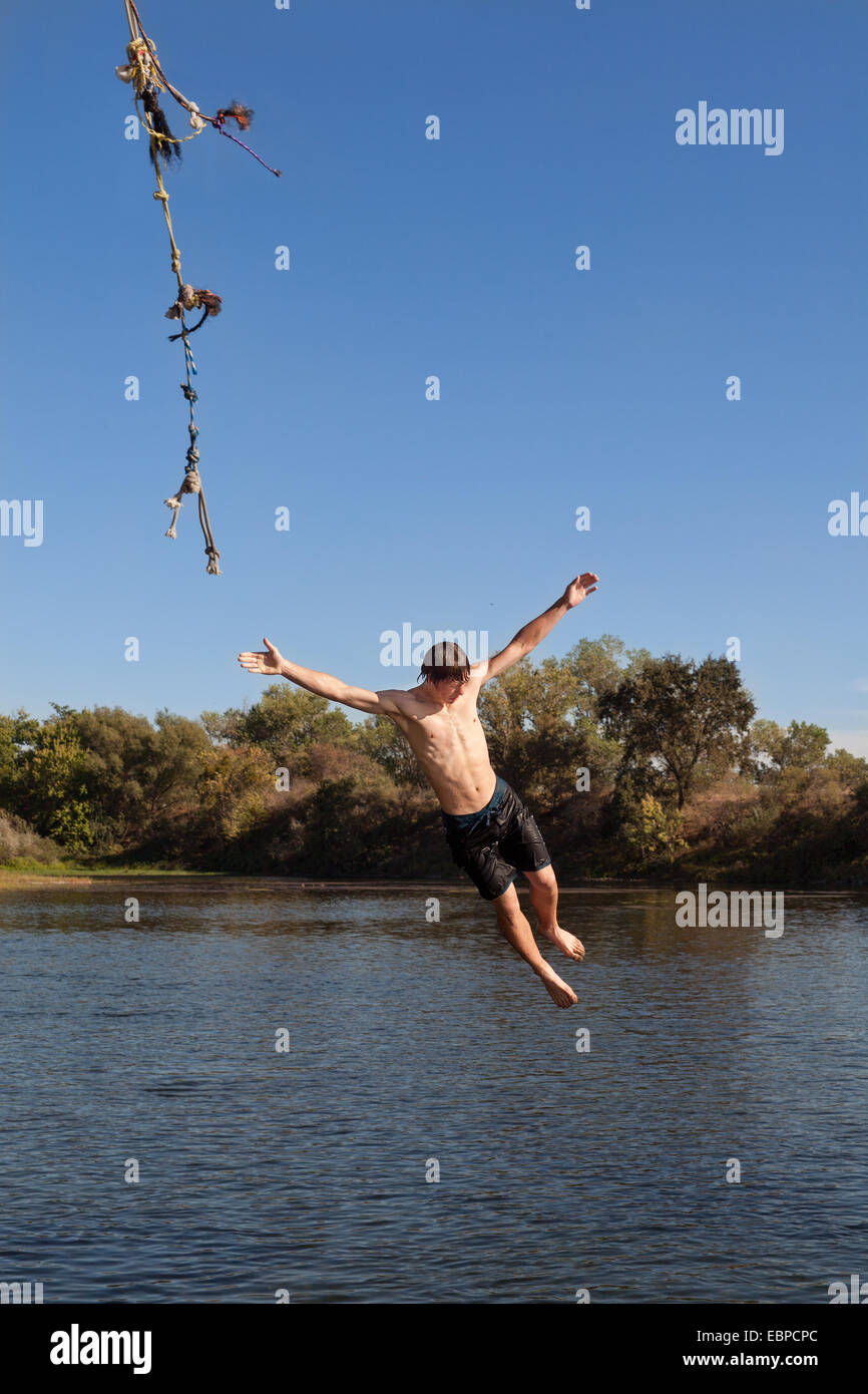 Teenage Boy Letting Go Of A Rope Swing Stock Photo