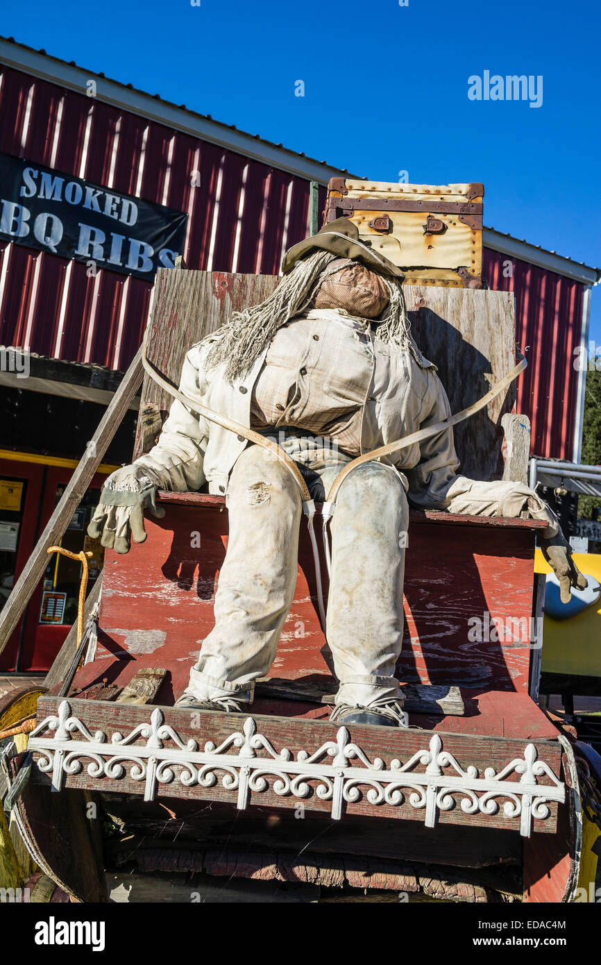 Dummy stage coach driver seated on the driver's seat of an old stage coach in a display of the old west outside of a restaurant Stock Photo