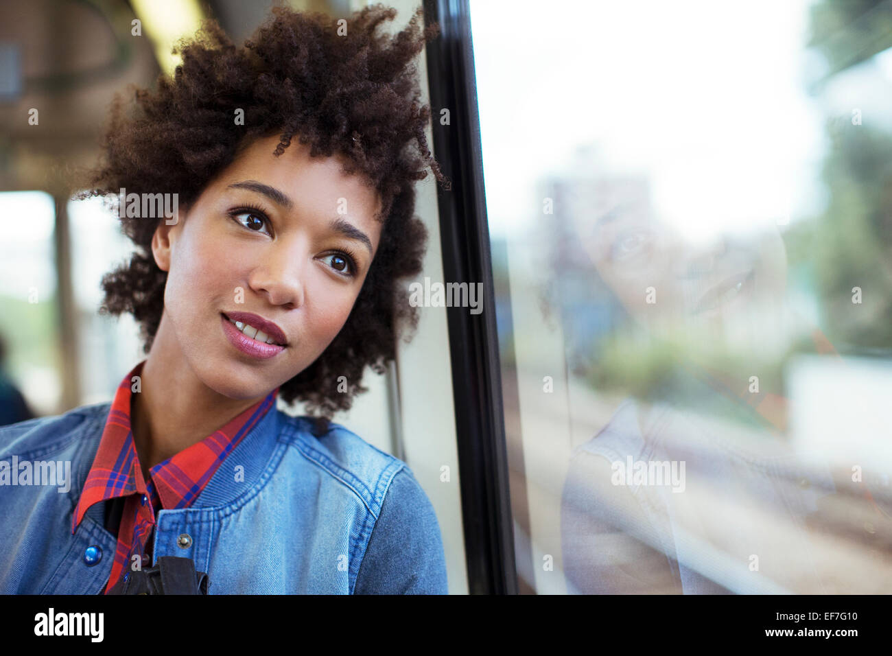 Daydreaming woman looking out train window Stock Photo