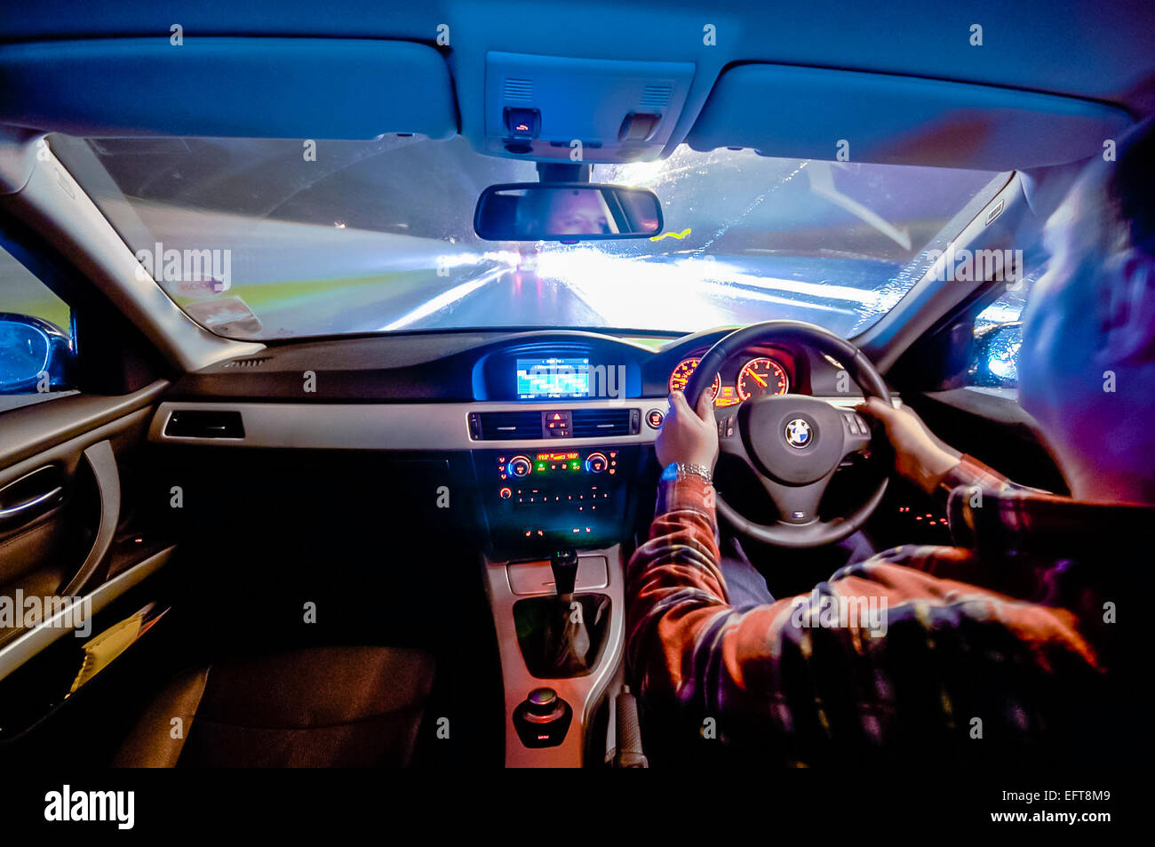 A man drives a BMW car at night. Stock Photo