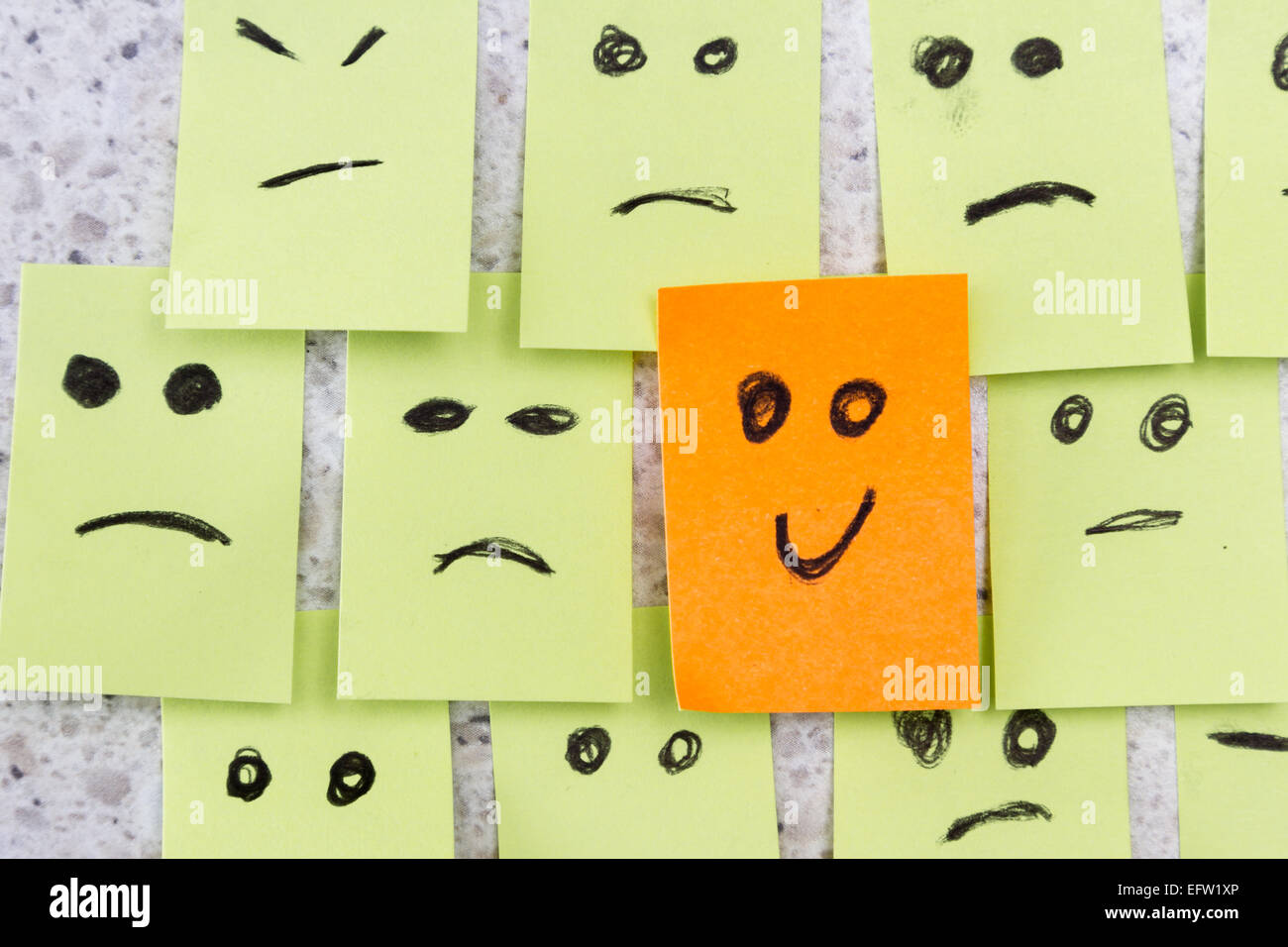 concept for a positive attitude with small office notes with multiple faces and one that stands out with a smile Stock Photo