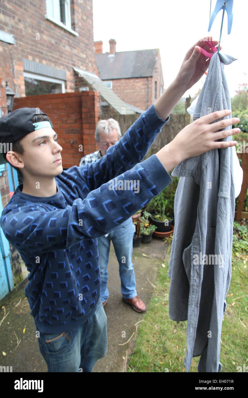 Teenage boy hanging out washing with grandfather - model released Stock Photo