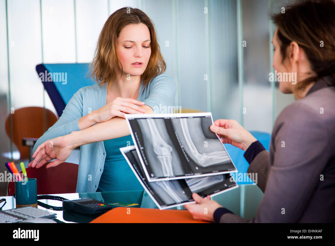 Doctor examining and commenting patient's elbow X-ray. Stock Photo