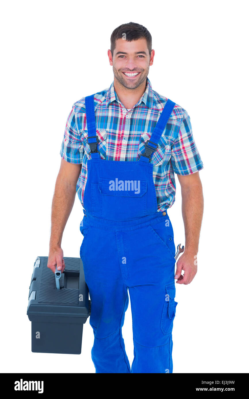 Happy handyman in coveralls carrying toolbox Stock Photo