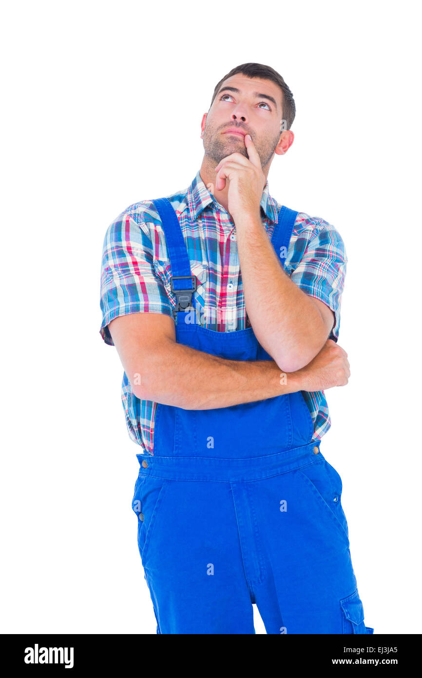 Thoughtful handyman in coveralls looking up Stock Photo