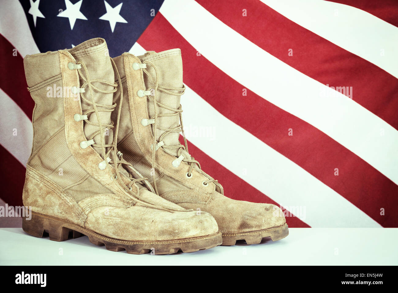 Old combat boots with American flag in the background Stock Photo