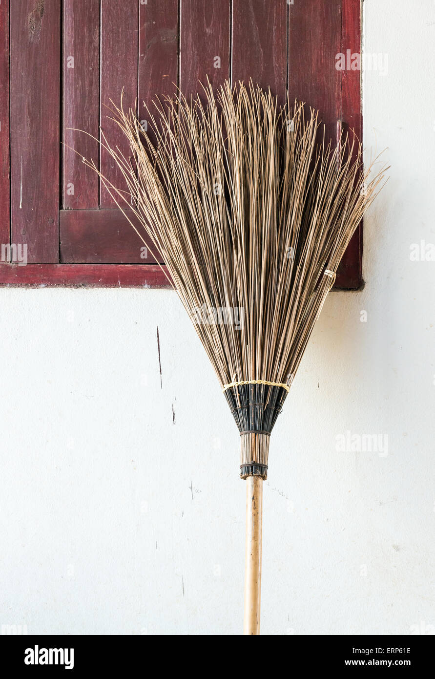 Old coconut brooms is laying near the window of countryside house. Stock Photo