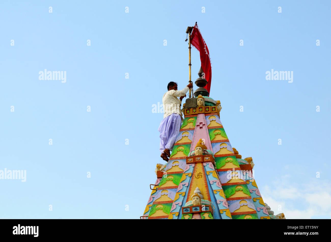 Tying flag mast to pole on top of temple at Mindiyada near Anjaar ; Kutch ; Gujarat ; India Stock Photo