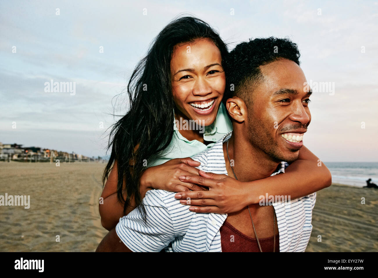 Man carrying girlfriend piggyback on beach Stock Photo