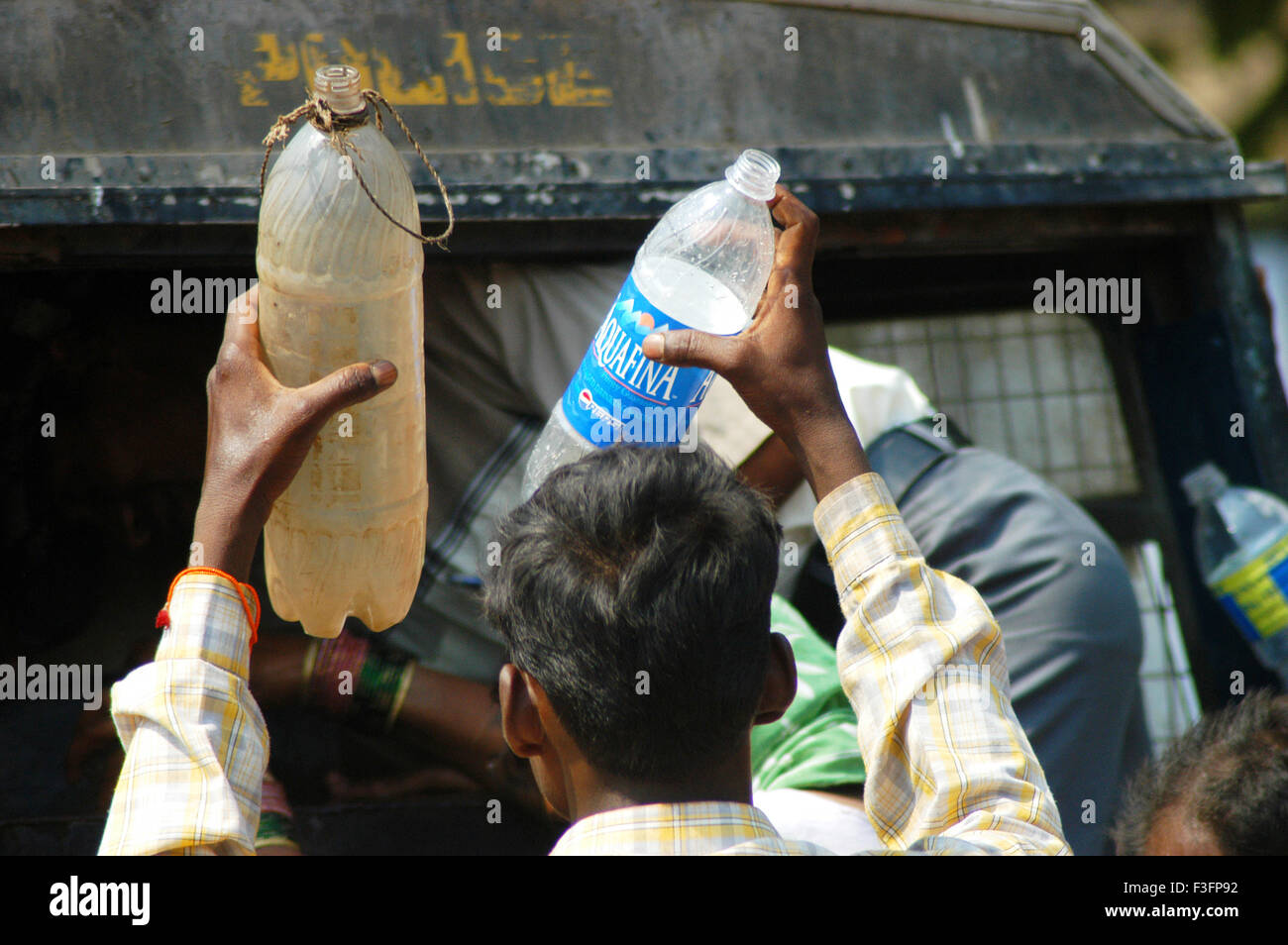 Poor man holds two plastic bottles to fill drinking water ; Bombay Mumbai ; Maharashtra ; India Stock Photo