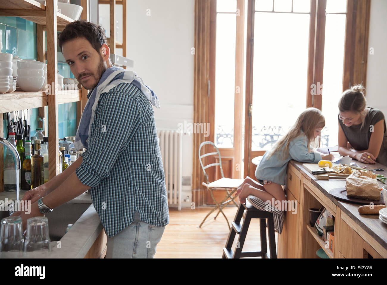 Family in kitchen, man doing dishes in foreground Stock Photo