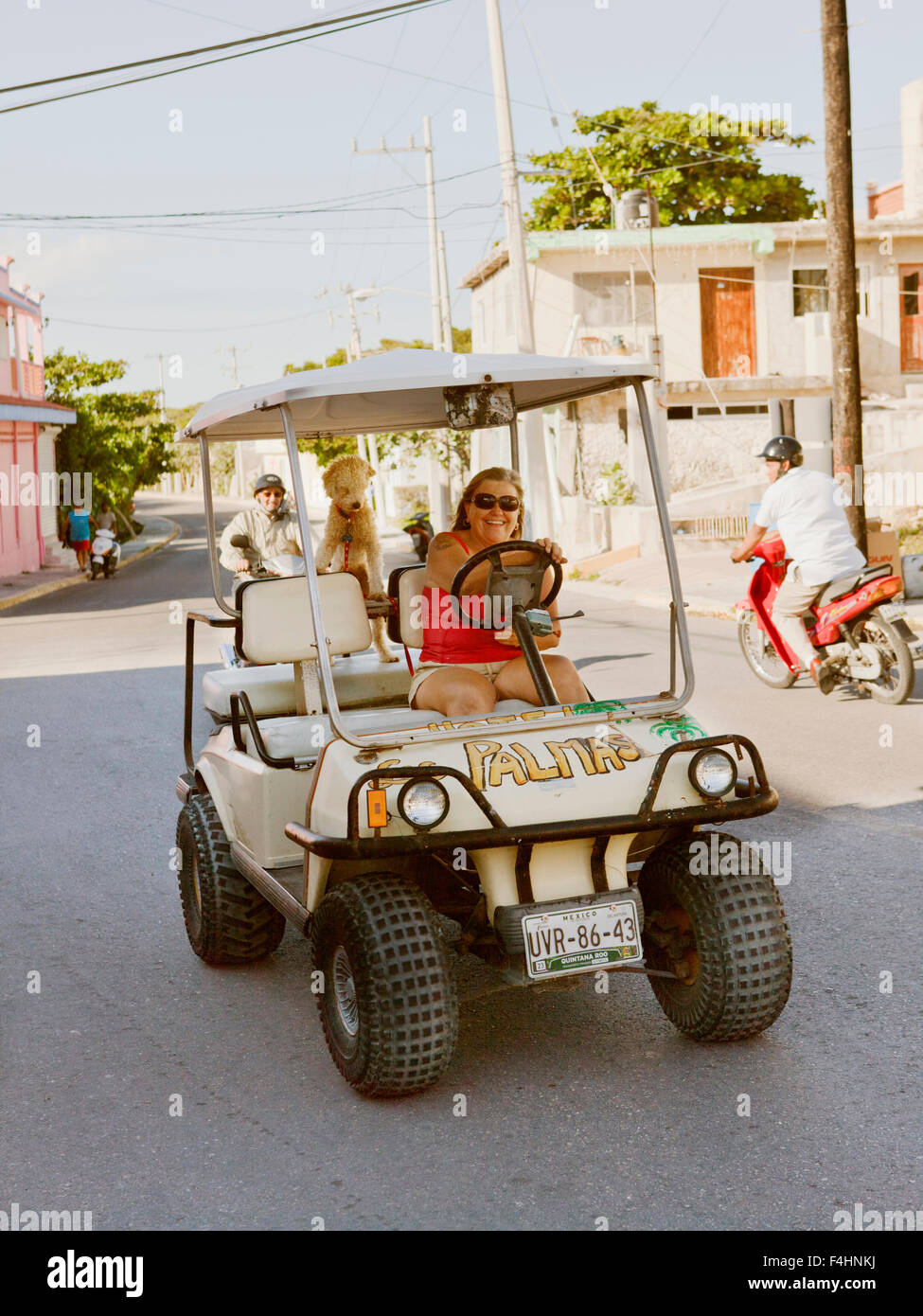 A local ex- pat drives her golf cart through town. IIsla Mujeres, Quintana Roo, Mexico. Stock Photo