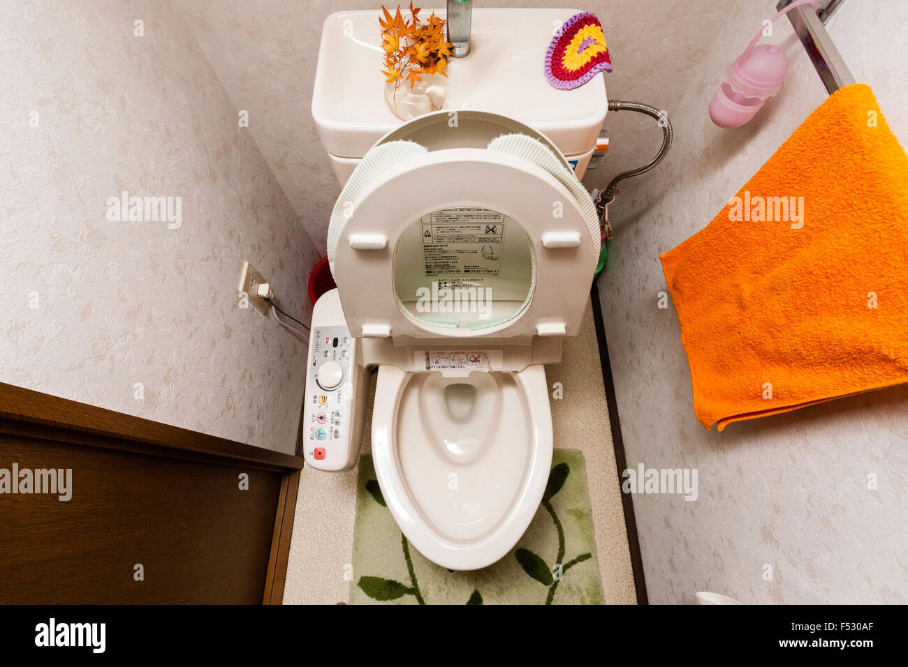 Japanese toilet, lavatory. Seat up. High angle-view looking down at electric toilet and the side control panel. Wash basin is top of cistern. Stock Photo