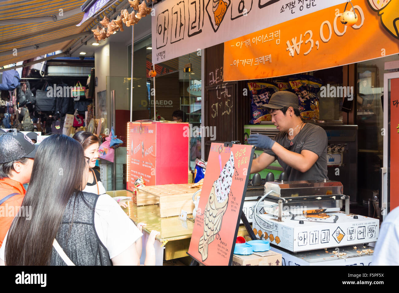 SEOUL, SOUTH KOREA - SEPTEMBER 12 2015: People queue to buy food in a popular stall in the busy Namdaemun market in Seoul. Stock Photo