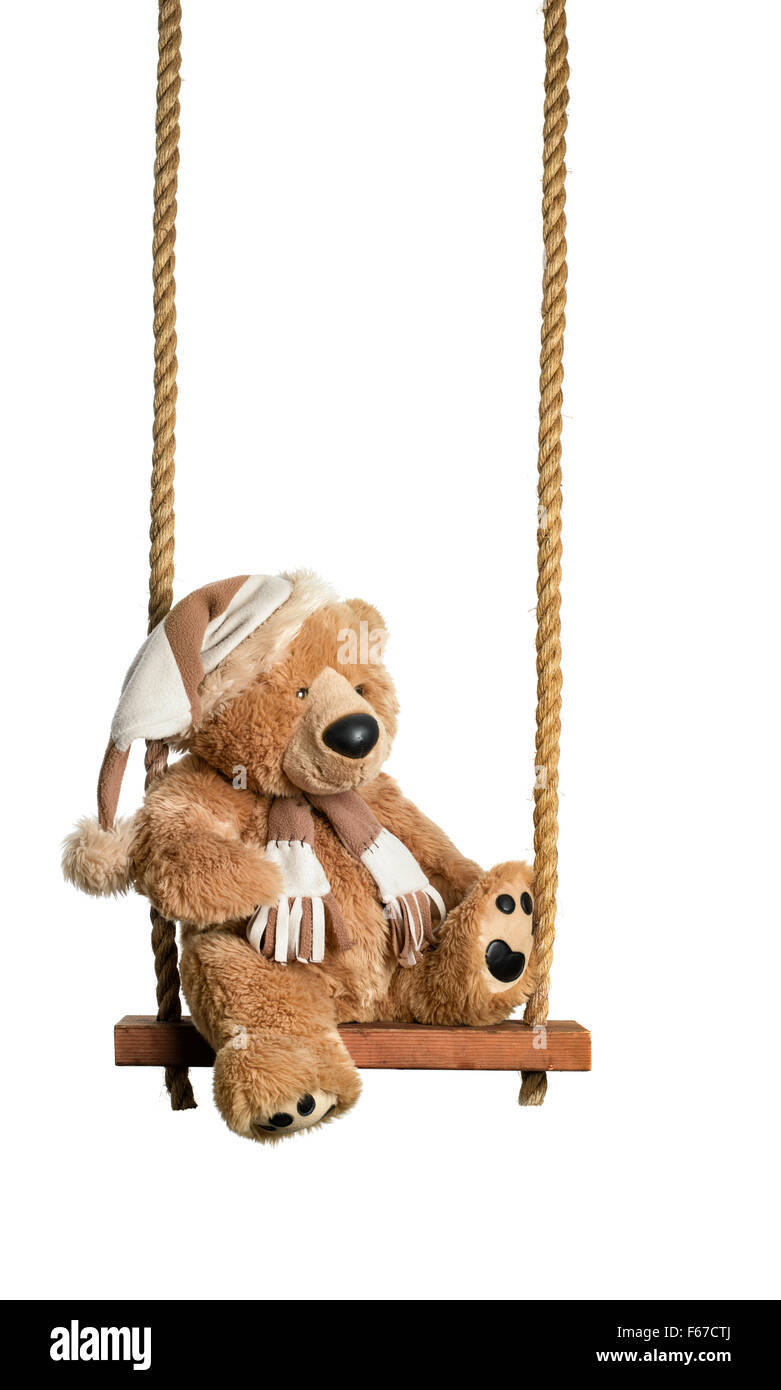 Brown teddy bear sitting on rustic wooden swing isolated on a white background Stock Photo