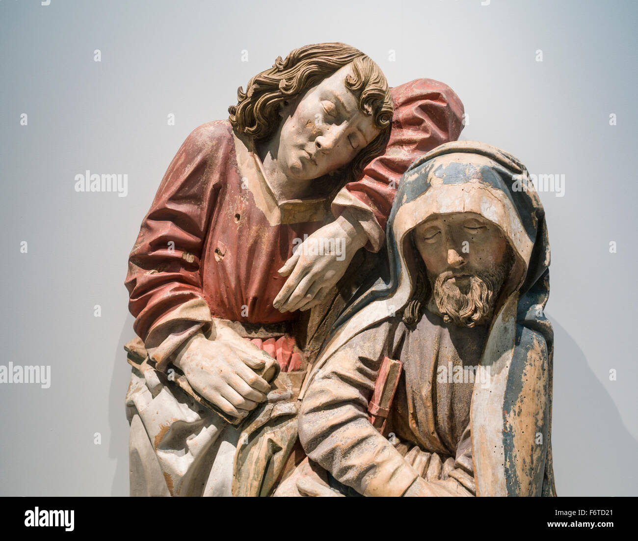 Medieval Wooden sculpture of two Figures. A worn statue of a two figures in cloaks with books, its paint flaking Stock Photo